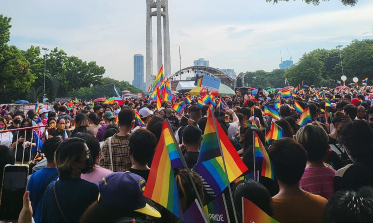 LGBTQ+ pride flags on a crowded parade 